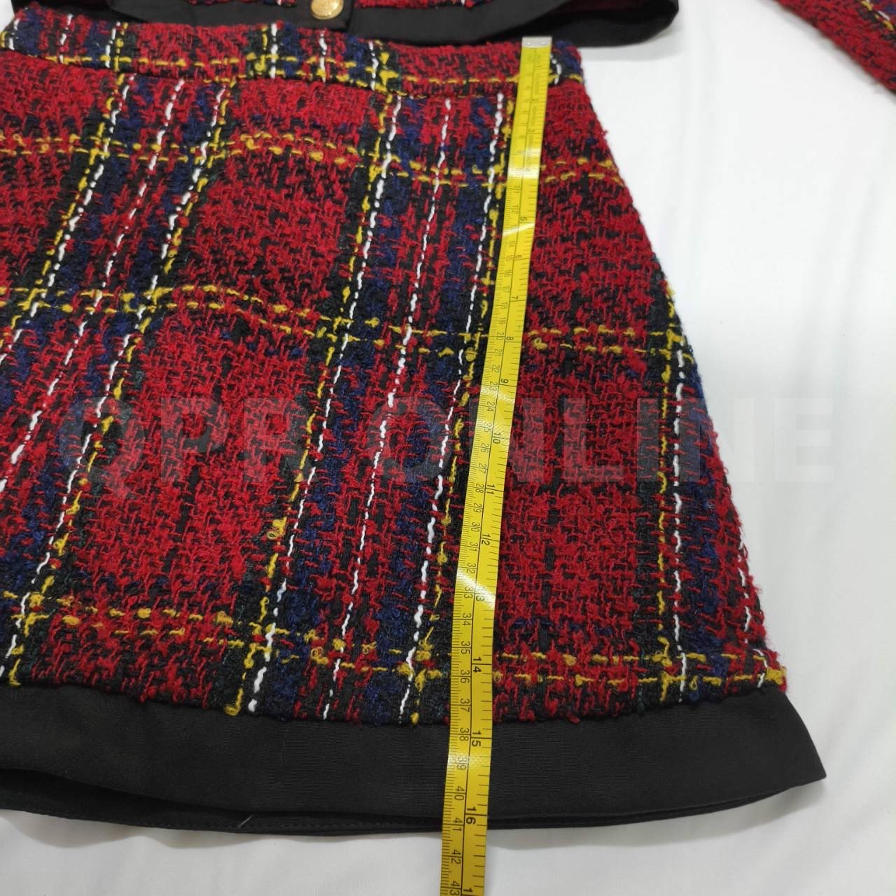 มี (S) Maria Diamond เสื้อครอปแขนยาวผ้าทวีดทอลายตารางสีแดงสลับน้ำเงินและเหลือง โดดเด่นด้วยปกเสื้อสีดำขนาดใหญ่